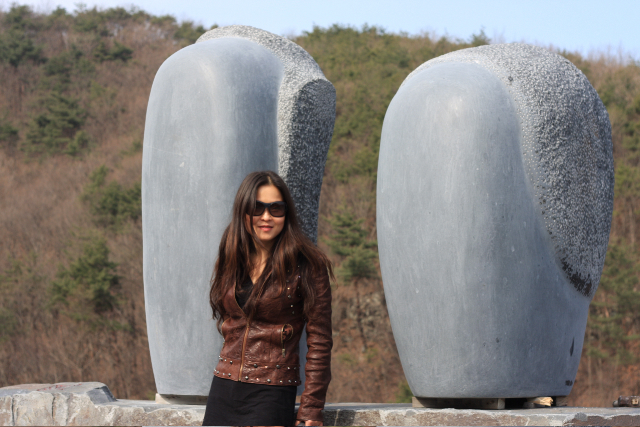 Chinese stone sculptor Zhang Yaxi poses next to her stone sculpture installation of two carved black marble heads. A strong, stylized artwork!